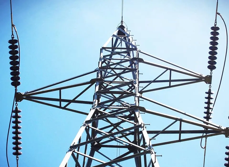High-voltage transmission tower with insulators against a blue sky